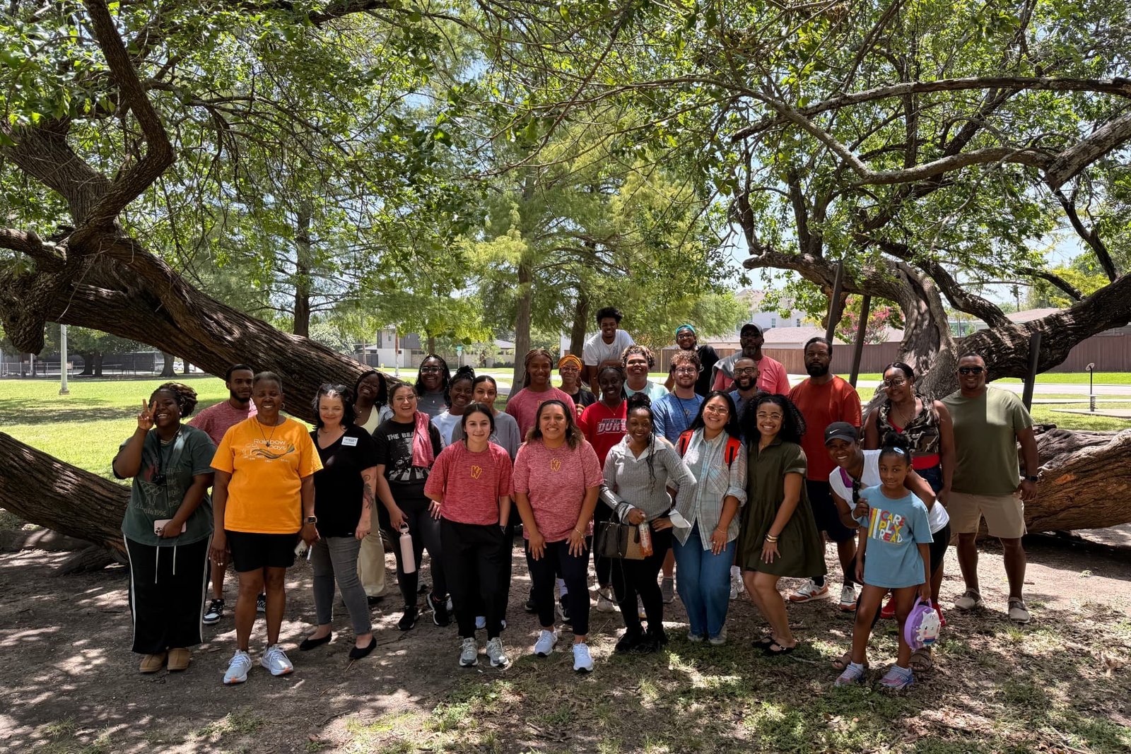 Camp staff and volunteers gathered together under a large shade tree